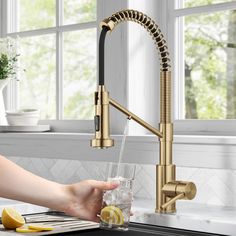 a person holding a glass in front of a kitchen faucet with water running from it