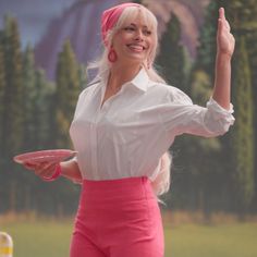 a woman in pink pants and white shirt holding a frisbee with her right hand