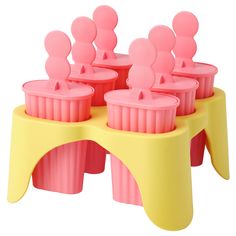 pink and yellow plastic cups sitting on top of a table with people in the cup holders