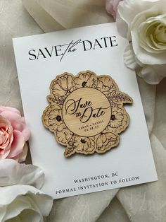 save the date wooden badge with flowers on it next to a card that says save the date