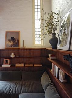 a living room with bookshelves, couch and vase on top of the shelves