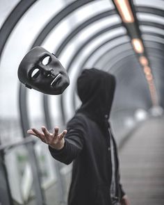 a person in a black hoodie with a mask on their face and hands out