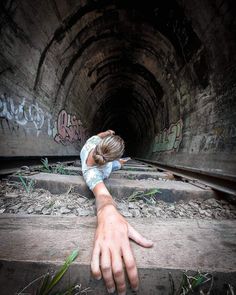 a person with their hand on the ground in front of a train track that has graffiti all over it