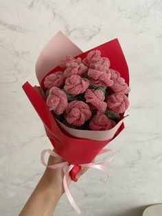 a hand holding a red paper wrapped bouquet filled with raspberries