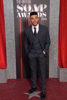 a man wearing a suit and tie standing in front of a star on the red carpet