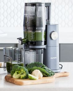 there is a blender and some vegetables on the counter next to eachother