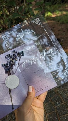 a person holding up a purple and silver wedding card with flowers on the inside of it