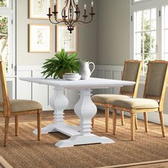 a dining room table with chairs and a potted plant in the center on top