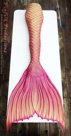 a drawing of a pink mermaid tail on top of a white board with wood planks