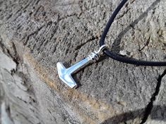 a necklace with an arrow on it sitting on top of a rock