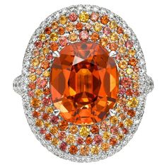 Introducing the 6.75 Carat Mandarin Garnet "Sunrise" Ring by Merkaba Jewelry Beverly Hills, an extraordinary creation that epitomizes luxury and artistic brilliance. This radiant piece features a stunning 6.75-carat oval Mandarin Garnet, known for its fiery orange hue, expertly set in timeless platinum. Surrounding the centerpiece are 0.98 carats of rare fancy-colored sapphires and 1.41 carats of round brilliant diamonds, forming a vibrant interplay of color and sparkle. Designed to captivate co Sunrise Ring, Orange Gemstones, Colored Sapphires, Mandarin Garnet, Chrome Tourmaline, Fancy Sapphire, Orange Jewelry, Genie Bottle, Demantoid Garnet