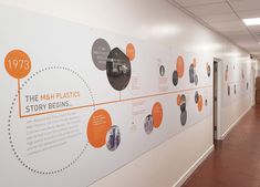 an office hallway with white walls and orange graphics on the wall, along with brown tile flooring