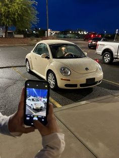 a person holding up a cell phone to take a picture of a car in the parking lot