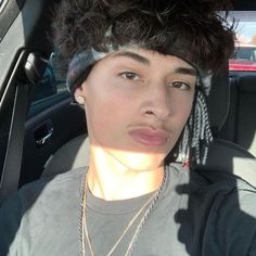 a young man in a car wearing a hat with dreadlocks on his head