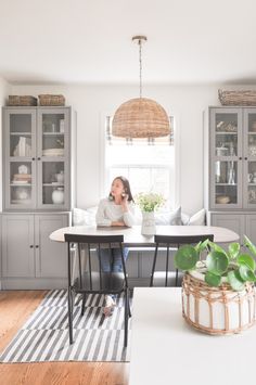 a woman sitting at a kitchen table talking on the phone