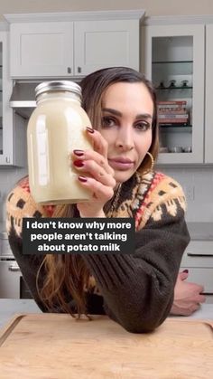 a woman sitting at a table with a jar of milk in front of her and the caption i don't know why