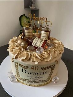 a birthday cake decorated with liquor bottles and gold decorations on top of a white plate