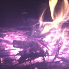 the fire is blazing in the dark with bright yellow and purple flames coming out of it