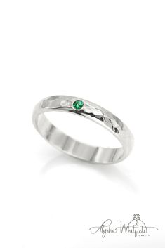 A simple emerald wedding band design with a luxurious hammered finish.  Natural gemstone in Palladium White Gold. Emerald Ring With Single Diamond For Anniversary, Promise Solitaire Emerald Ring With Round Cut, Classic Emerald Promise Ring With Birthstone, Promise Emerald Ring With Round Cut For May Birthstone, Promise Emerald Ring May Birthstone Round Cut, Green Ring With Single Diamond In Fine Jewelry Style, Green Diamond Ring In Fine Jewelry Style, Emerald Solitaire Ring For Anniversary With Round Band, Round Diamond Cut Emerald Promise Ring