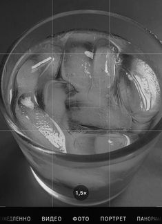 a glass filled with ice sitting on top of a table next to a black and white photo