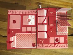 an open book with red and white designs on it sitting on top of a wooden floor