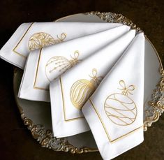 four white and gold christmas napkins on a plate