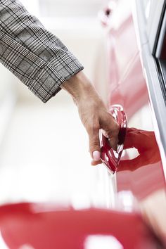 a person's hand on the door handle of a red car