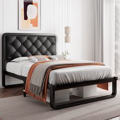 a bed with a black headboard and foot board in a white room next to a window