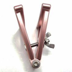 a pair of pink metal clamps with screws on white background, top view