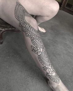 a woman sitting on top of a chair with her legs covered in hendi tattoos