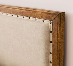 an upholstered headboard with metal studs and wood trim on the sides