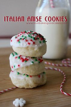 three cookies with white frosting and sprinkles next to a glass of milk