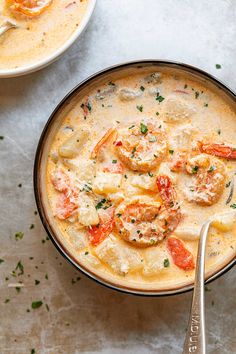 two bowls of soup with shrimp and dumplings in them on a white counter top