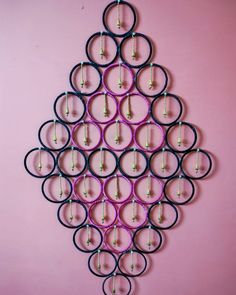 there is a circular wall hanging made out of pairs of scissors on the pink wall