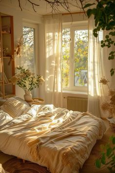 an unmade bed sitting in front of a window next to a potted plant