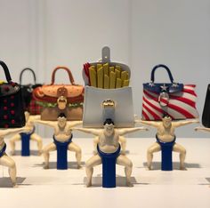 several small figurines are posed in front of purses