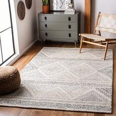 a living room with a chair and rug on the wooden floor next to a dresser