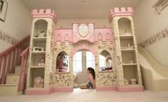 a woman sitting on the floor in front of a pink castle like room with stairs