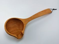 a wooden spoon on a white surface with a black string hanging from the handle and an empty bowl in the middle