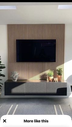 a flat screen tv mounted to the side of a wall next to a potted plant