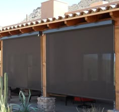 an outdoor covered patio area with privacy screens and cacti in the back ground