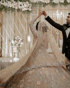 the bride and groom are dancing together at their wedding reception in front of an elaborate floral backdrop