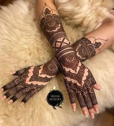 a woman's hands with henna tattoos on her arm and hand, sitting next to a furry animal