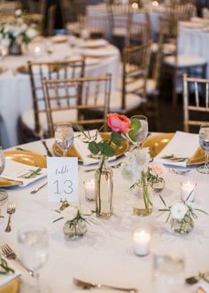 the table is set with white and gold plates, silverware, and pink roses