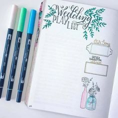 an open planner with markers and pens next to it