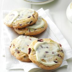 three cookies with white icing and cranberries are on top of a napkin