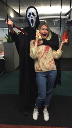 a woman standing next to a man in a scream mask and holding an orange object