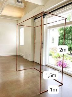 an empty room with two large windows and a metal frame on the floor in front of it