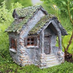 a small house with moss growing on it's roof in the middle of some grass