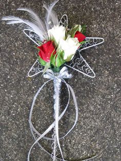 a boutonniere with white and red roses tied to it on the ground